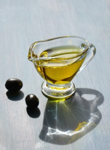 glass jug of olive oil with oilves