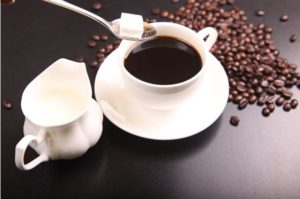 Cup of coffee with milk jug and coffee beans