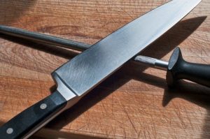 Chefs knife and sharpener on wooden chopping board