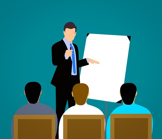 Cartoon drawing of man in front of flip chart teaching 3 people