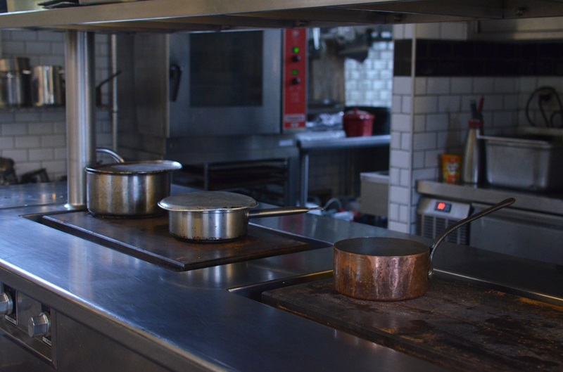 stainless steel counter and cooking equipment in commercial kitchen with pots and pans