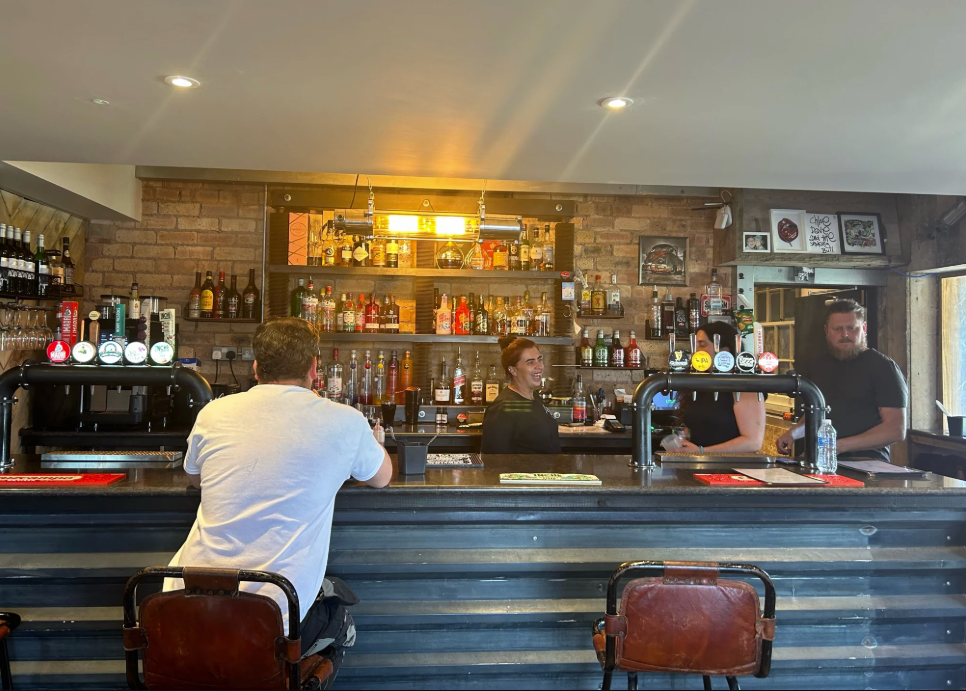 bar with people behind and man sitting on stool