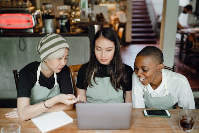 three people sitting at laptop looking at the screen