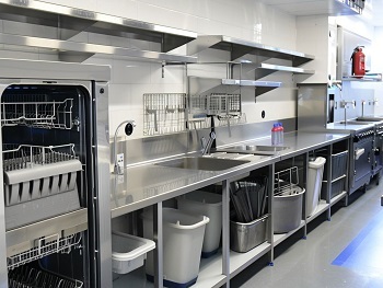 stainless steel dishwasher, sinks and tabling in a commercial kitchen